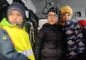 Dzieci oglądają wnętrze wozu strażackiego.