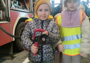 Dzieci pozują do zdjęcia z wężem strażackim.
