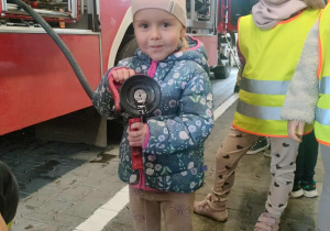 Dzieci pozują do zdjęcia z wężem strażackim.