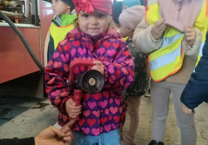 Dzieci pozują do zdjęcia z wężem strażackim.