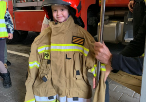 Dziecko pozuje do zdjęcia w stroju strażaka.