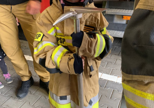 Dziecko pozuje do zdjęcia w stroju strażaka.