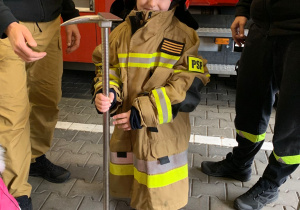 Dziecko pozuje do zdjęcia w stroju strażaka.