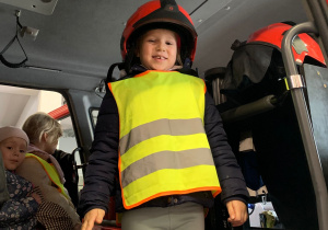 Dziecko pozuje do zdjęcia w stroju strażaka.