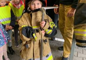 Dziecko pozuje do zdjęcia w stroju strażaka.