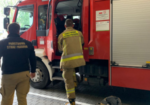 Strażak wsiada do wozu na akcję.