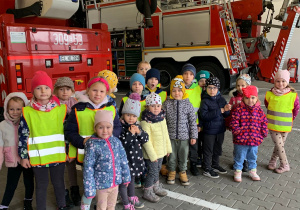 Dzieci pozują do zdjęcia na tle wozu strażackiego.