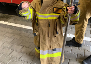 Dziecko pozuje do zdjęcia w stroju strażaka.