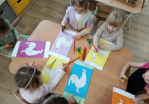 Dzieci wykonują pracę plastyczną - koguty na ręcznikach.