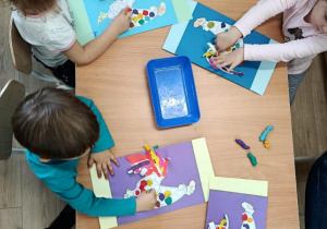 Dzieci wykonują pracę plastyczną - koguty na ręcznikach.