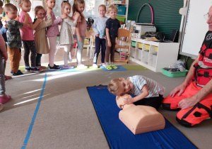 Chłopiec ćwiczy na fantomie pod kierunkiem ratownika medycznego.