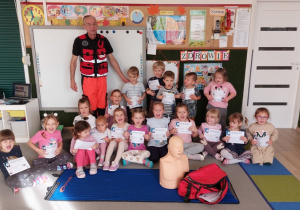 Dzieci pozują do zdjęcia z ratownikiem medycznym.