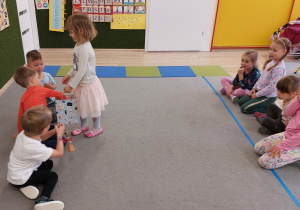 Dziewczynka wręcza chłopcu prezent.