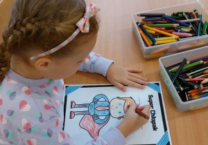 Dziewczynka maluje dyplom dla chłopca.