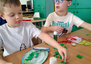 Chłopiec wykleja słoik bibułą.