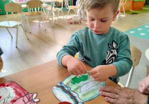 Dzieci wyklejają pracę bibułą.