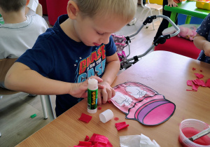 Dzieci wyklejają pracę bibułą.