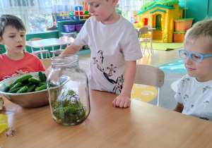 Dzieci wkładają ogórki do słoika.