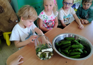 Dzieci wkładają ogórki do słoika.