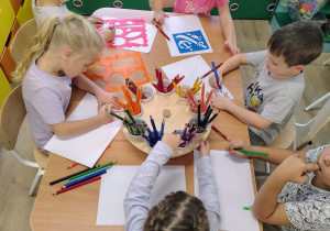 Dzieci siedzą przy stoliczku i rysują.