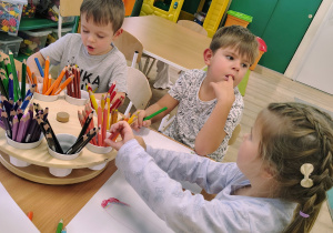 Dzieci siedzą przy stoliczku i rysują.
