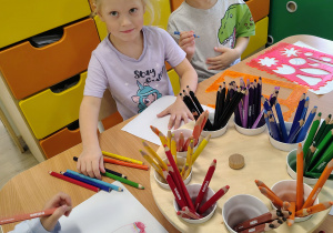Dzieci siedzą przy stoliczku i rysują.