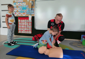 Chłopiec uciska manekina.