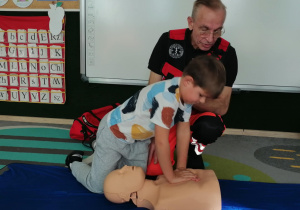 Chłopiec uciska manekina.