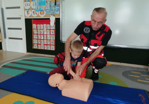 Chłopiec uciska manekina.