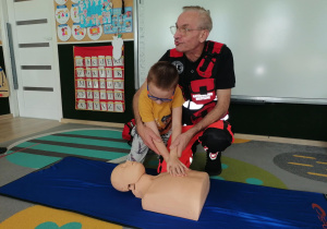 Chłopiec uciska manekina.