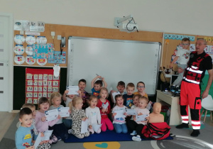 Dzieci pozują z ratownikiem do zdjęcia.