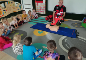 Dzieci siedzą i słuchają ratownika.