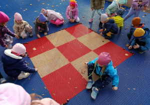 Dzieci bawią się kasztanami na tarasie.