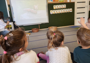 Dzieci siedzą na dywanie.