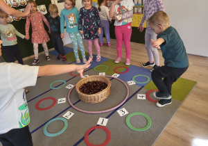 Dzieci stoją, bawią się w grę z cyframi i kasztanami.