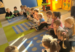 Dzieci siedzą na dywanie.