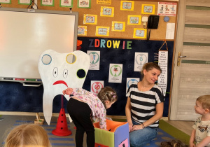 Dziewczynka sięga do kostki po piłkę.