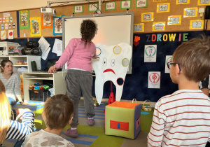 Dziewczynka rzuca piłką do dziury w zębie.