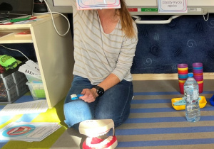 Nauczycielka prezentuje 1 z plansz prawidłowego mycia zębów.