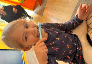 Dziewczynka prezentuje technikę mycia zębów.