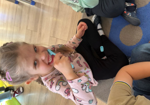 Dziewczynka prezentuje technikę mycia zębów.