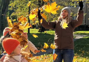 Nauczycielka z dziećmi podrzuca liście.