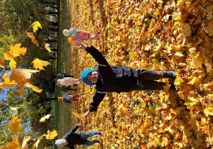 Chłopiec podrzuca liście.