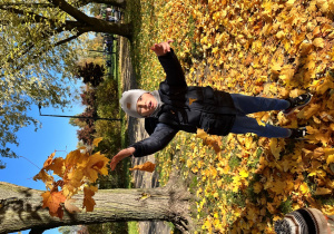 Chłopiec podrzuca liście.