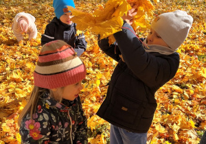 Chłopiec rzuca liścmi w dziewczynkę.