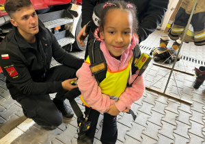 Dziecko z plecakiem strażaka.