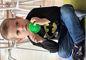 Dziecko siedzi z piłką.