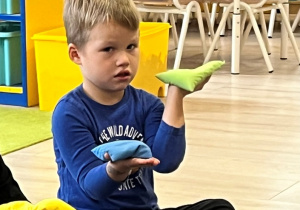 Chłopiec z woreczkami na dłoniach, porównuje ciężar.