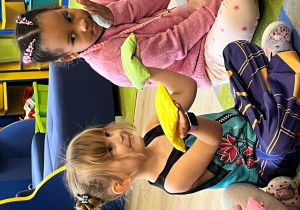 Dziewczynka z woreczkami na dłoniach, porównuje ciężar.