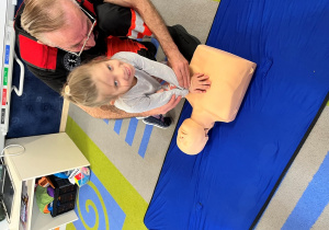 Dziecko z ratownikiem układa dłonie na fantomie.